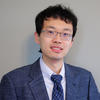 Tianshu Feng in a blue suit and tie and silver-framed glasses for his faculty profile at George Mason University.